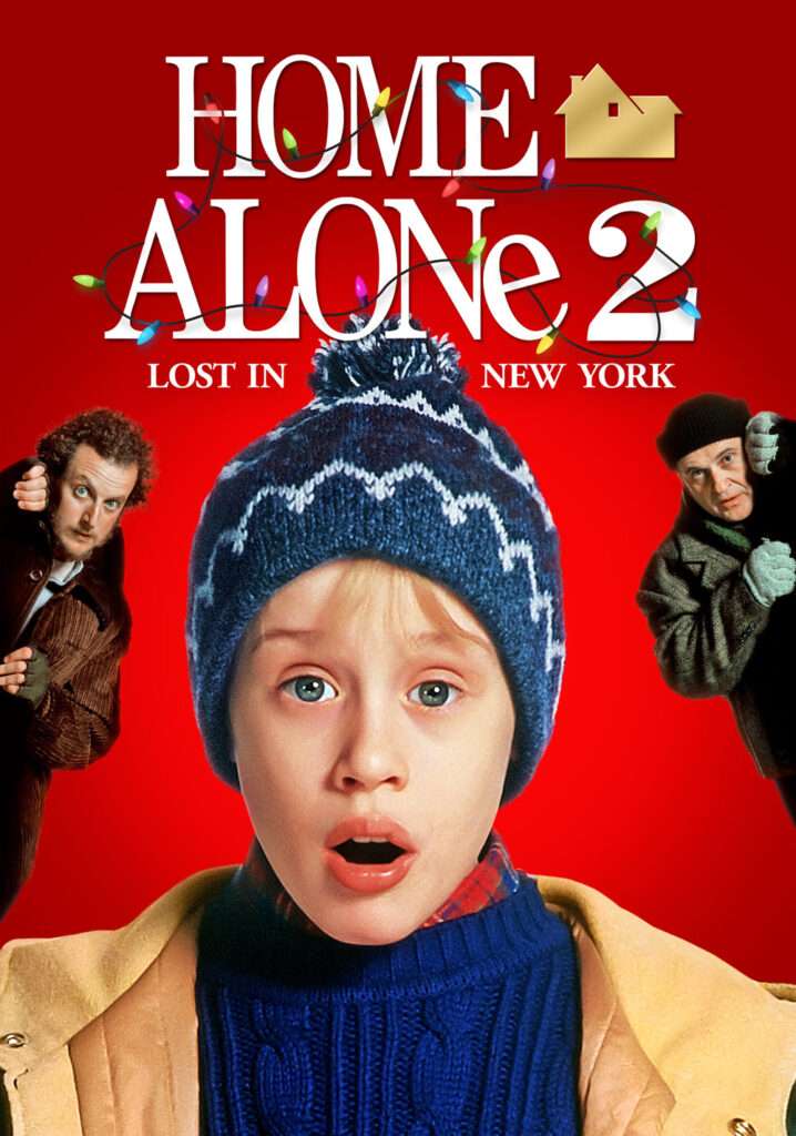 Poster for Home Alone 2: Lost in New York featuring Kevin McCallister in the center wearing a blue winter hat with a pom-pom and a shocked expression. The two burglars appear on either side—one peeking in from the left with a surprised look, the other from the right with his fists raised. The background is bright red with the title ‘HOME ALONe 2: LOST IN NEW YORK’ in large white and gold letters, decorated with colorful Christmas lights.